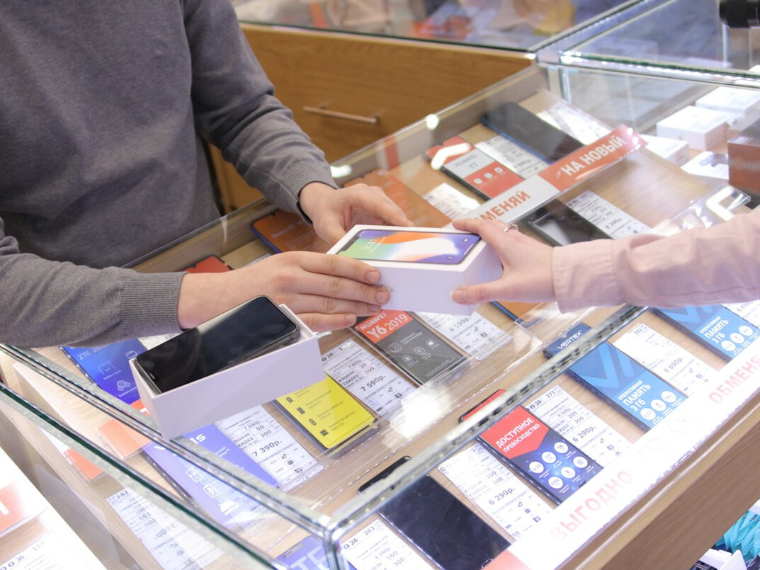 Shop owner checking trend alerts on a smartphone in a store